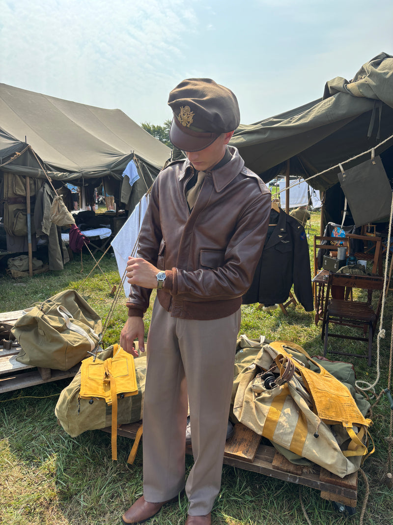 a WWII Pilot reenactor checks his watch against a dioramic background